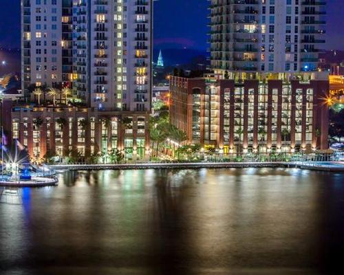 Photo of Jacksonville's 南岸河边漫步 at night from across the river. 建筑物的灯光反射在水面上.